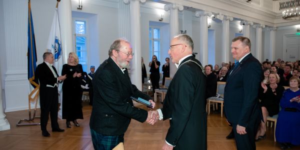 Two men in the centre of the frame shaking hands