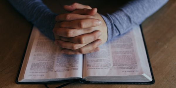 Hands in prayer over Bible