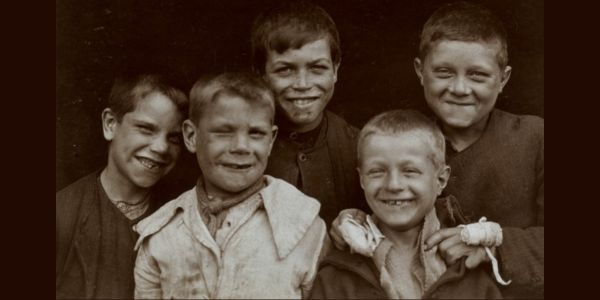 A black and white photo from 1904 showing four young boys, smiling. One has a bandage on his hand.