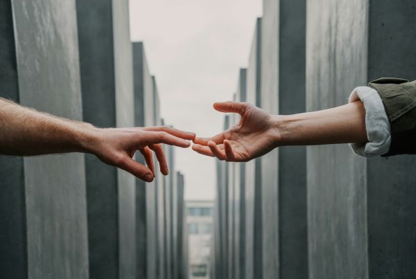 two hands reaching between concrete pillars