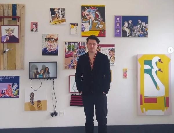 Artist Aaron Jolley with art work in a gallery space