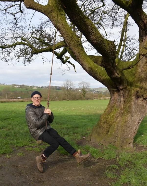 Artist Jo Nash on a swing on a tree