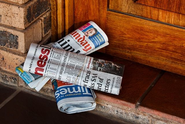 Three rolled up newspapers on a doorstep.