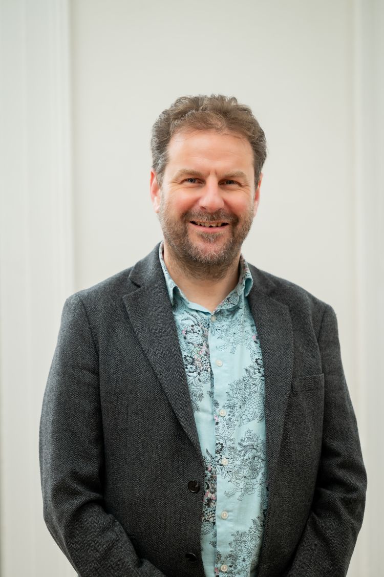 A man smiles for the camera against a white background