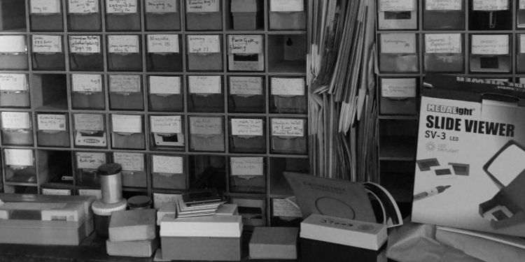 Stack of boxes containing slides in an archive with a slide reader bottom right