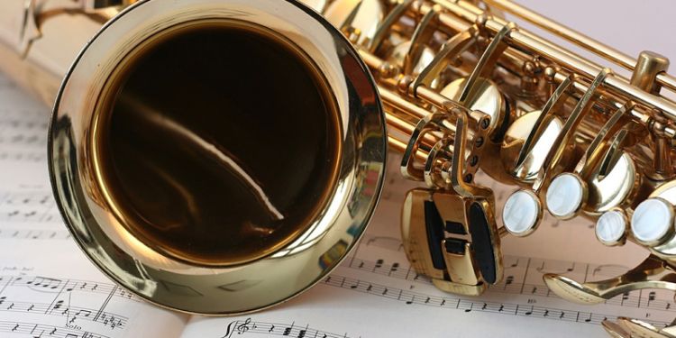 Saxophone lying on top of music sheets