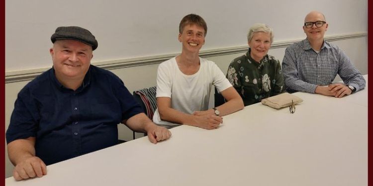 Four people sit smiling at a table