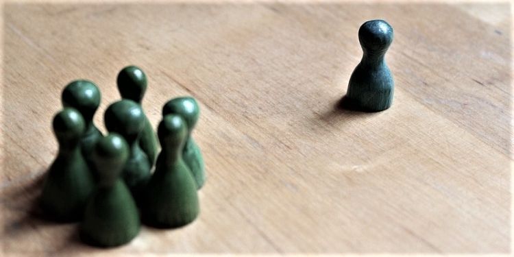 Humanoid game counters grouped with one different colour on own