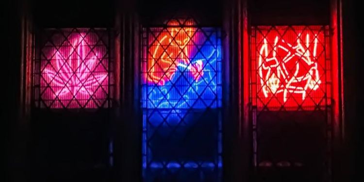 Three neon artworks shining through a church window