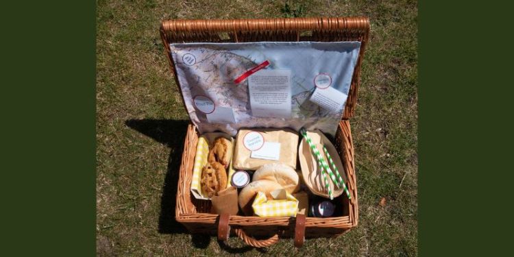 An open picnic basket with food, a map, and memories written on paper
