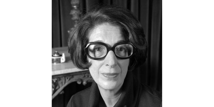 Black and white close up of a person with thick round glasses and bobbed dark hair.