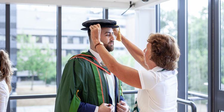 Student having gown fitted for graduation