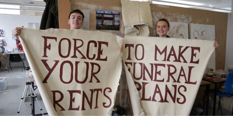 George Storm Fletcher and Isabelle Morse holding the 'Force your parents to make funeral plans' canvases