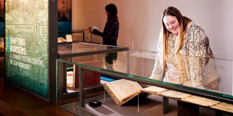 Person in a museum looking down into a glass display case of books