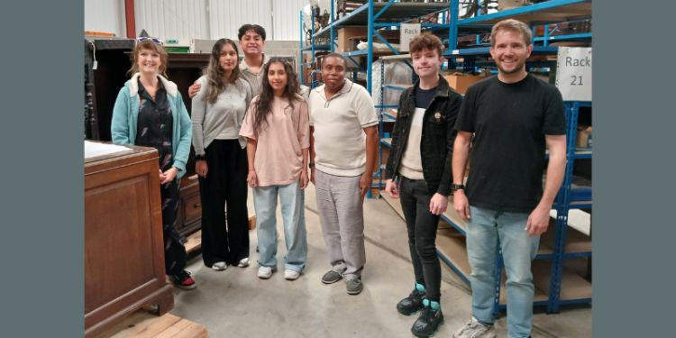 a group of young people surrounded by shelving in a warehouse