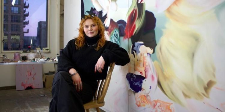 Photo of Izzie Beirne, seated, with painting.