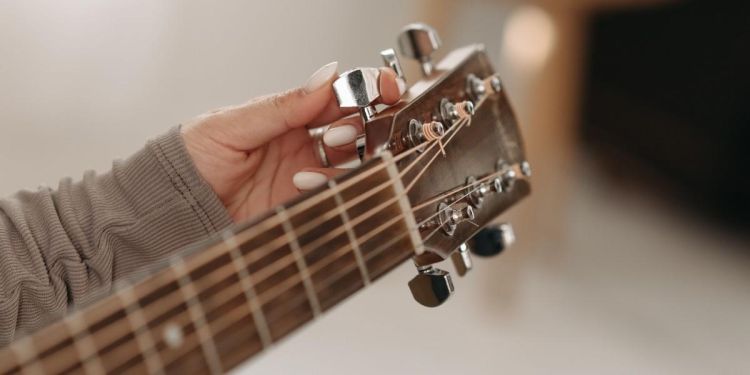 Person tuning an acoustic guitar