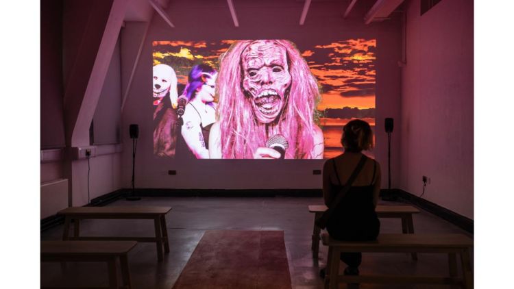 Astrid's work at the MA show 2024: an exhibition attendee watches Astrid's film projection