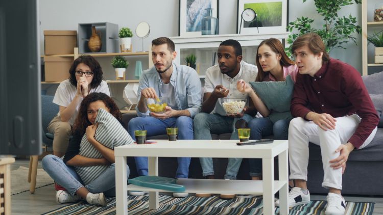 A group of people watch a TV together