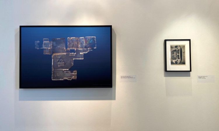 Artworks on a gallery wall. On the left is Point Cloud.v001: Bird’s Eye View by Stefani Byrd. On the right is Poltergeist 12 by Robin Miller.