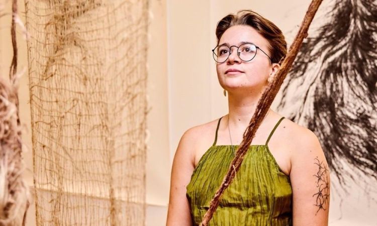 Artist Alice Boot with their work in a gallery