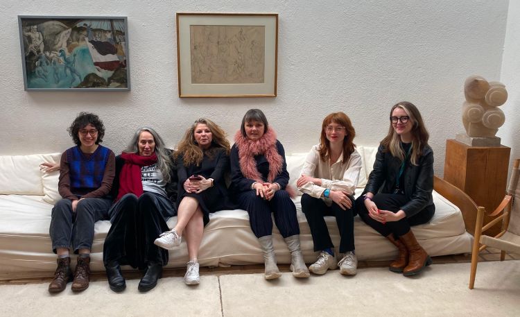 Six people seated next to artworks