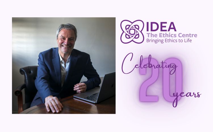 Gavin Esler sat at a desk to the left, IDEA logo and the words celebrating 20 years to the right