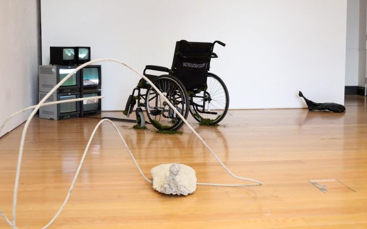 Artworks in a gallery - monitors, wheelchair, sandbags, concrete, steel rebar