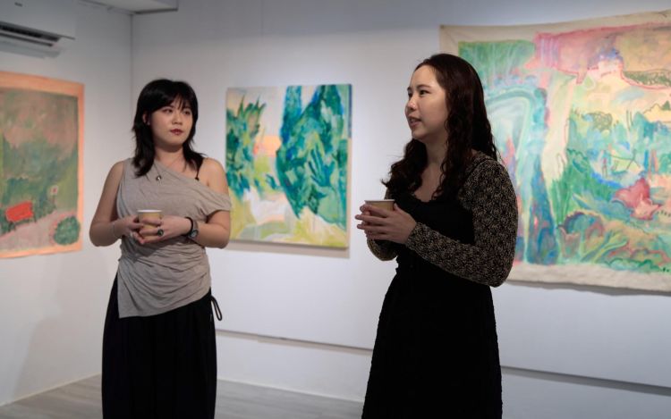 Two people in a gallery with artwork on the walls