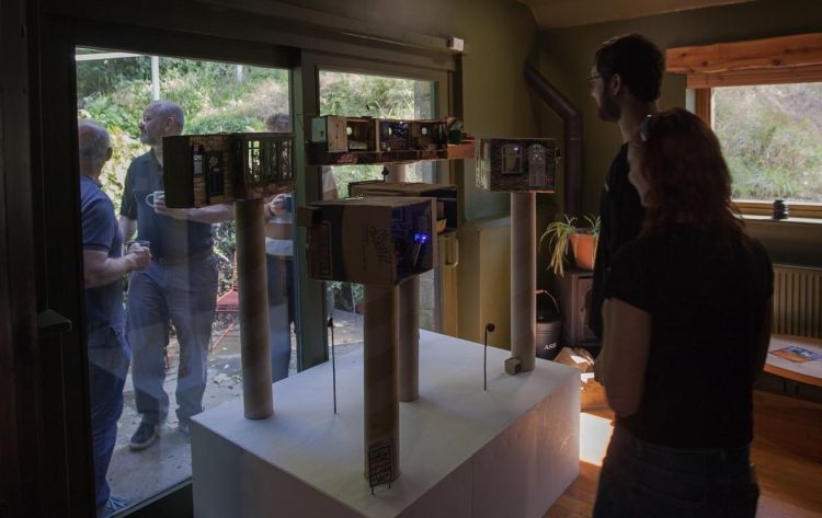 People looking at an installation of miniature houses in a gallery space