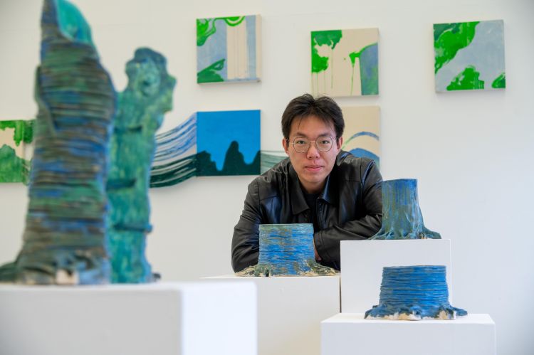 Artist Huayu Zhang with some of his artworks in a gallery