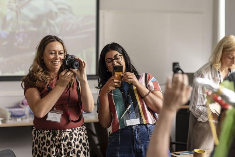 Two people taking photos of a person out of shot in the foreground