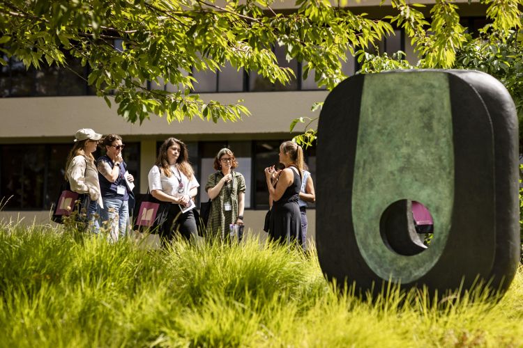 A group of people next to a sculpture by Barbara Hepworth on the University of Leeds campus