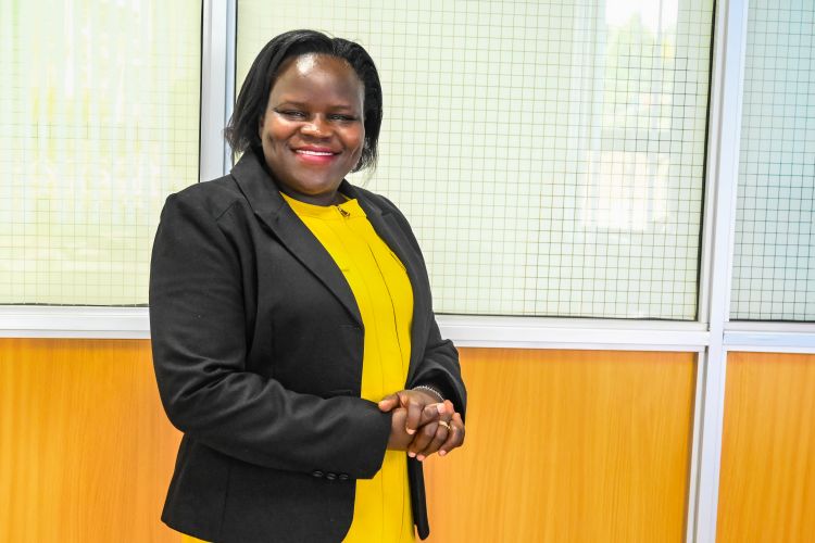 A woman stands in front of a bright background 