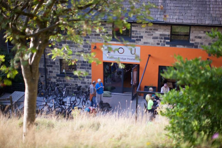 Exterior view of IOU Hebden Bridge Hostel building with grassed area and trees in foreground