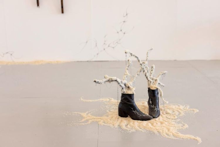 Artwork by Jun Rui Lo created with leather ankle boots, rice, clay, sticks, stones, hot-melt adhesive, wire, metal chain, safety pins, key