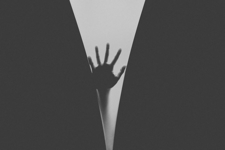 A hand in silhouette, reaching up into the void