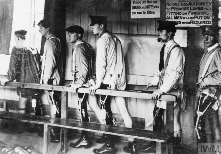 Black and white photograph showing men with amputations walking by using a handrail for support.