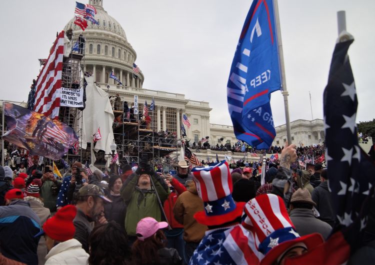 A crowd of people with American flags storm the US Capitol building