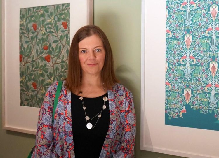 Artist Louise Atkinson next to two framed works in a gallery