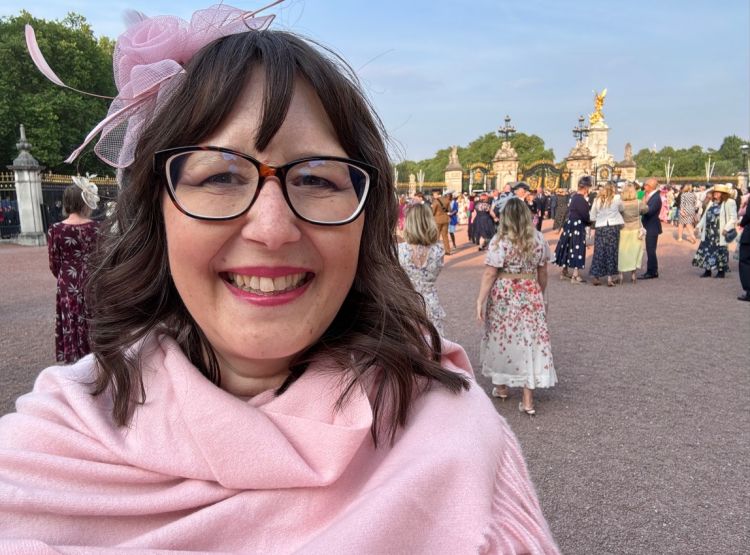 A woman in a pink coat smiles for the camera