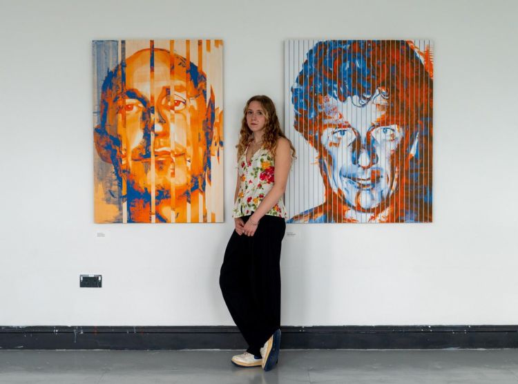 Artist Kirstin Harvie standing between two of her artworks.