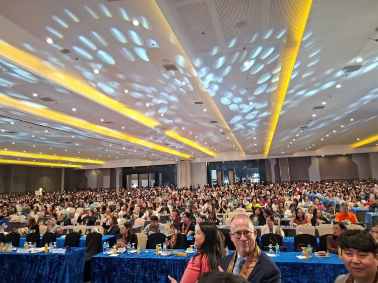 A hall full of people sat down waiting for a conference begin
