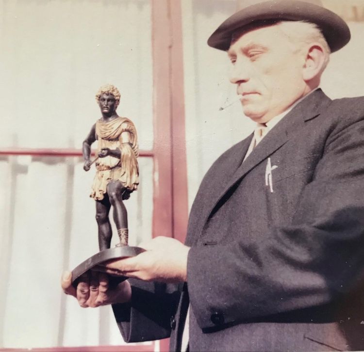 art dealer holding up a small sculpture