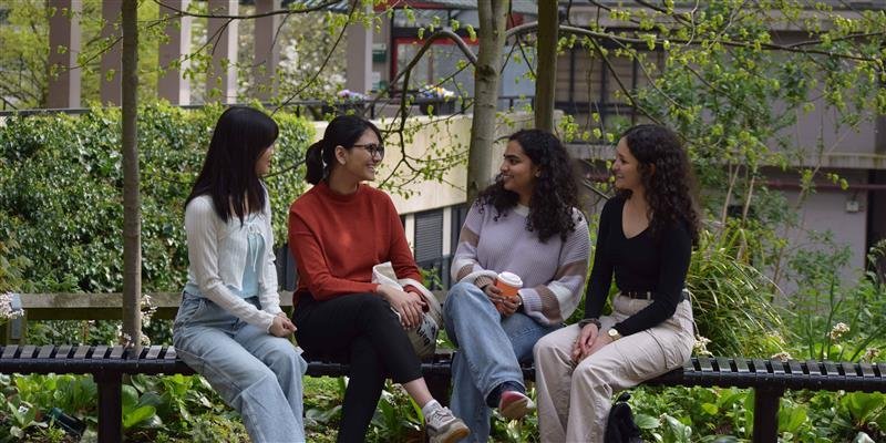 A small group of students sitting together outside on campus.