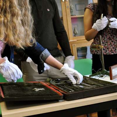 Students wearing protective gloves handling artefacts