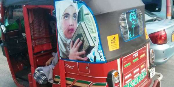 Motorized rickshaw with photo of a girl holding a holy book,