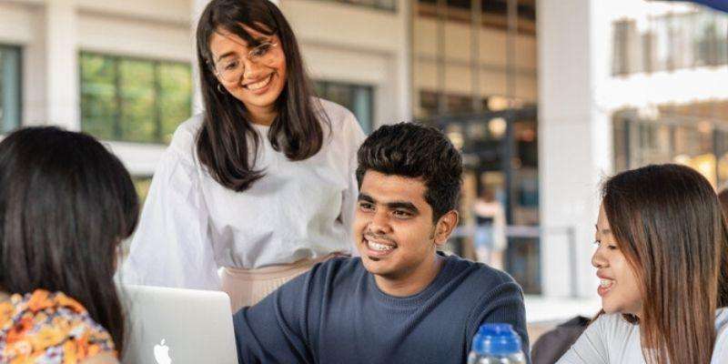 A group of four students studying outside together and smiling.