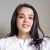 Headshot of FAHACS MA student Maria Navaro. Maria stands against a light grey background and wears a white top, she is smiling.