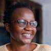 School of Fine Art, History of Art and Cultural Studies alumni, Laura Fungai Ganda. Laura is looking to the right of the frame and is smiling.